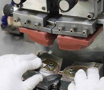 A pad printing machine applying logos to eyewear temples — the industry's workhorse customization method