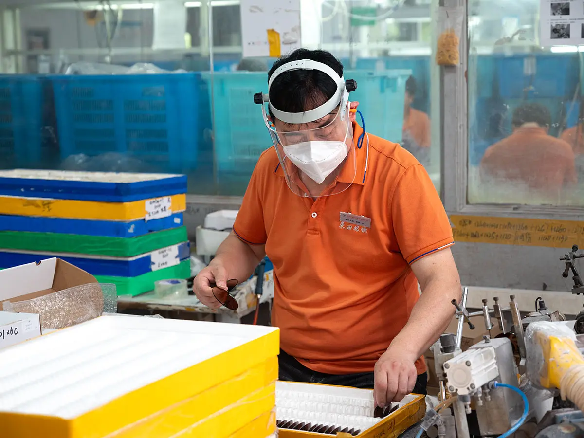 Worker performing final quality inspection on eyewear at Dongtian factory