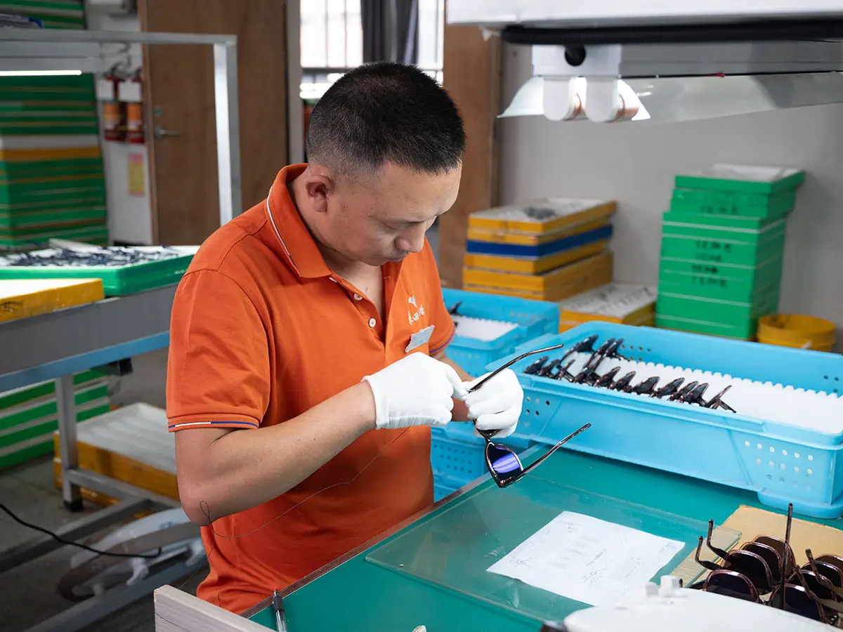 Worker performing final quality inspection on eyewear at Dongtian factory
