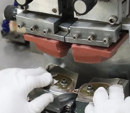 A pad printing machine applying logos to eyewear temples — the industry's workhorse customization method